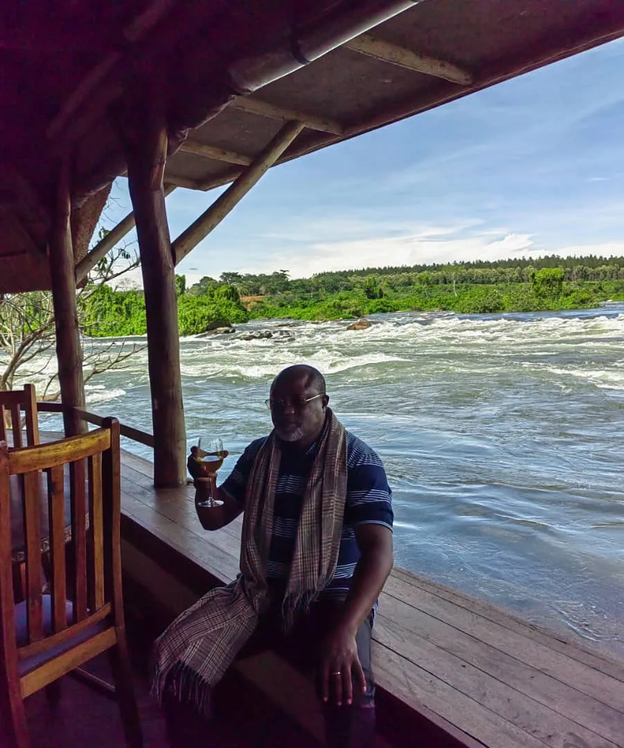 joseph-mbazzi-muguluma-by-the-river-bank-sipping-a-drink